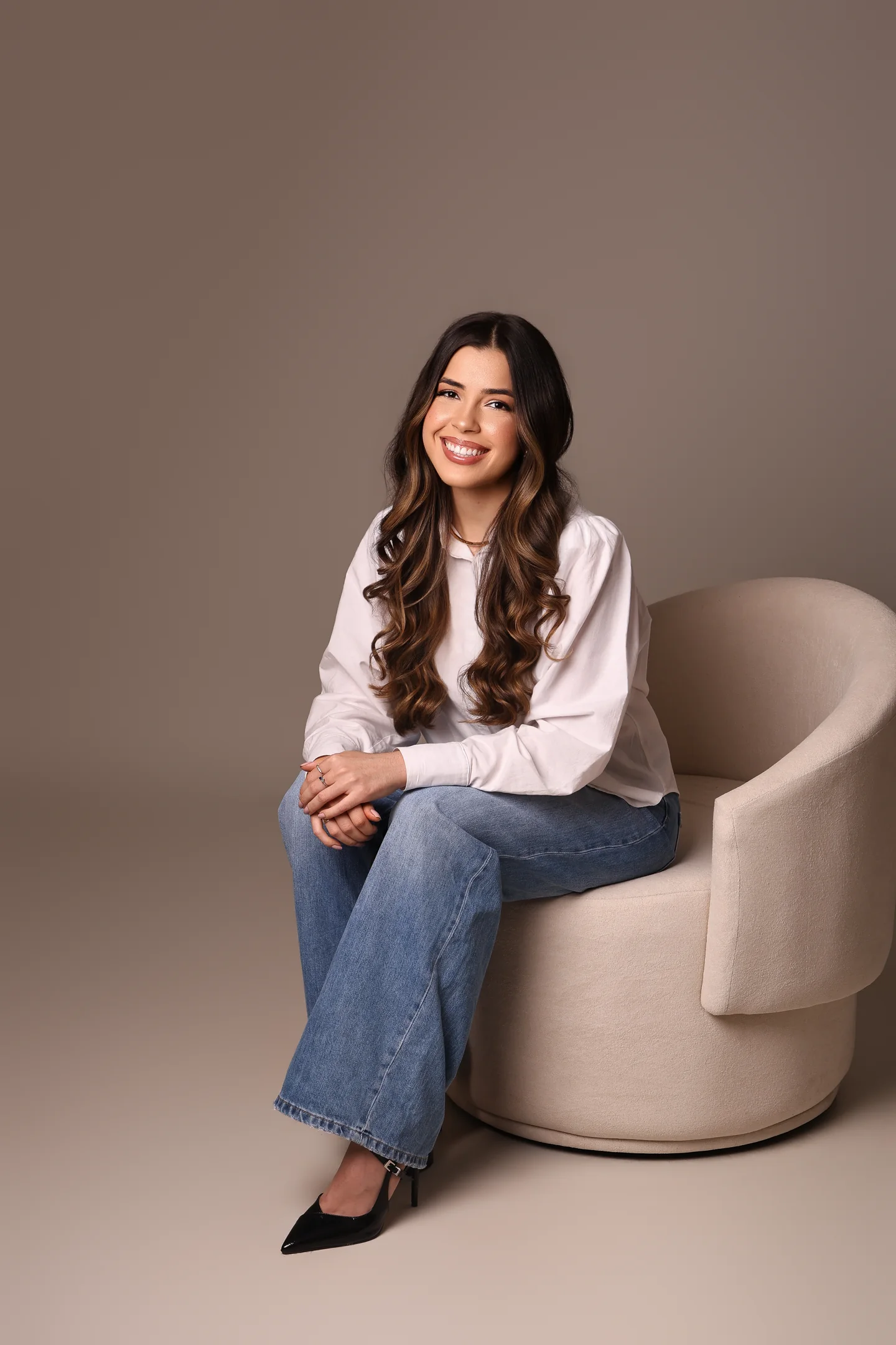 Vitória Lara sentada em uma poltrona clara